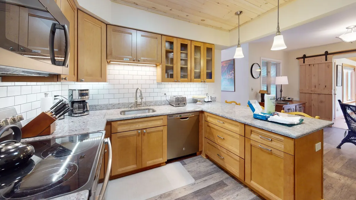 A cozy, functional kitchen space with granite countertops, stainless steel appliances, wooden cabinetry, and a subway tile backsplash. The layout suggests ample space for family meals and culinary activities.